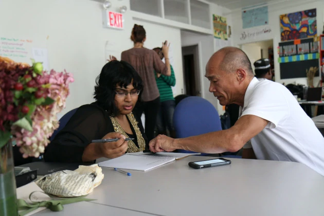 Man helping a woman fill out a job application.